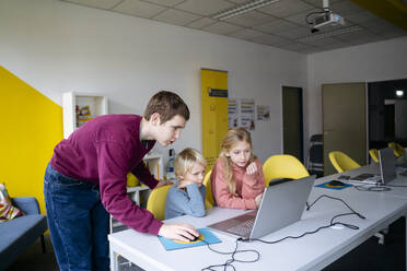 Jugendlicher hilft Schülern beim Programmieren im Klassenzimmer - NJAF00881