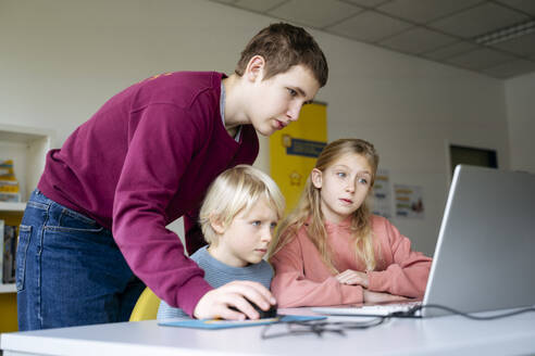 Jugendlicher hilft Schülern beim Programmieren im Klassenzimmer - NJAF00884