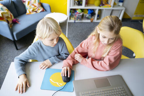 Mädchen und Junge teilen sich einen Laptop, um im Klassenzimmer Computerprogrammierung zu lernen - NJAF00886