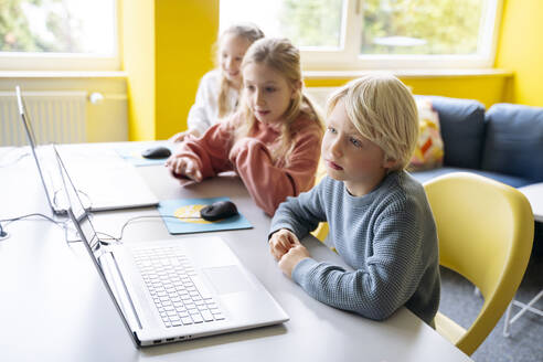 Blonder Junge sitzt mit Mädchen zusammen und lernt in einem Computer-Klassenzimmer - NJAF00890