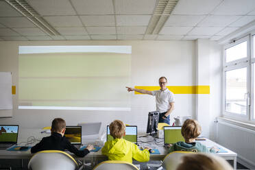 Professor zeigt auf Projektionsfläche und unterrichtet Computer für Jungen im Klassenzimmer - NJAF00899