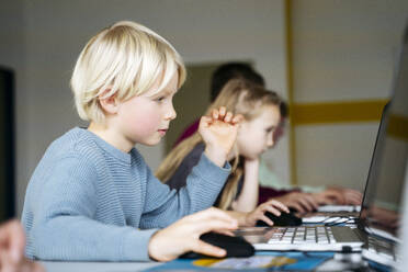 Blonder Junge lernt Codierung durch Laptop im Klassenzimmer - NJAF00916
