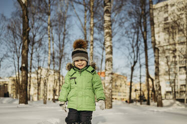Lächelnder Junge, der im Park im Schnee läuft - ANAF02747