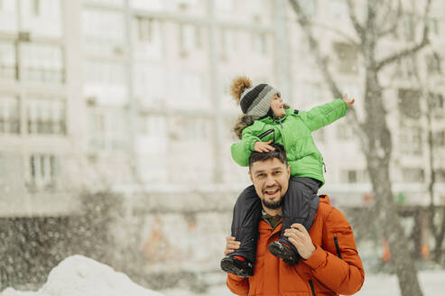 Glücklicher Vater trägt seinen Sohn auf den Schultern im Park im Winter - ANAF02758
