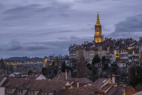 Switzerland, Bern Canton, Bern, Residential rooftops at dusk with Bern Minster in background - KEBF02847