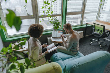 Multiracial colleagues discussing graph on laptop in meeting at coworking office - YTF01987