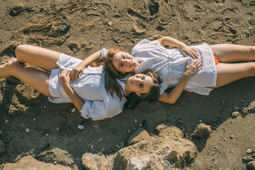 Lächelnde Mutter und Tochter auf Sand liegend - ADF00307