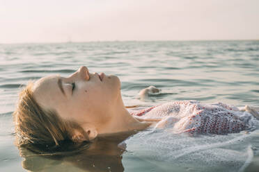 Unbekümmertes Teenager-Mädchen schwimmt auf dem Wasser im Meer - ADF00308