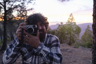 Mann fotografiert durch Kamera bei Sonnenuntergang - ASGF04944