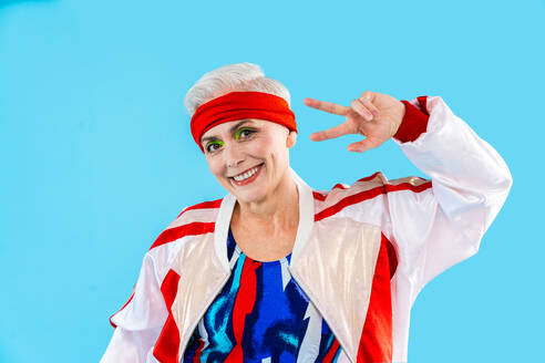 Happy and funny senior old woman wearing sportswear clothing on colorful background- Modern cool fancy grandmother portrait doing fitness workout, concepts about elderly, sport, healthy lifestyle and older people - DMDF10562