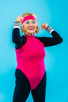 Happy and funny senior old woman wearing sportswear clothing on colorful background- Modern cool fancy grandmother portrait doing fitness workout, concepts about elderly, sport, healthy lifestyle and older people - DMDF10584