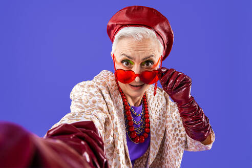 Happy and funny senior old woman wearing fashinable clothing on colorful background- Modern cool fancy grandmother portrait, concepts about elderly and older people - DMDF10683