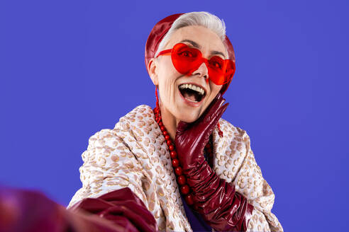 Happy and funny senior old woman wearing fashinable clothing on colorful background- Modern cool fancy grandmother portrait, concepts about elderly and older people - DMDF10685