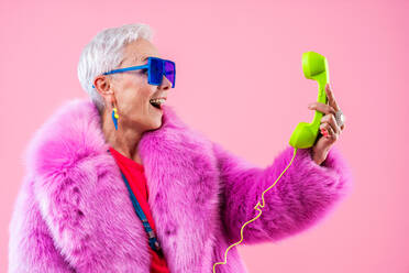 Happy and funny senior old woman wearing fashinable clothing on colorful background- Modern cool fancy grandmother portrait, concepts about elderly and older people - DMDF10745