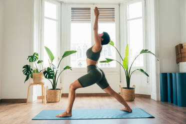 Beautiful sporty girl making yoga training in the gym studio. Young woman coach with short hair performing yoga and acroyoga poses, warming up for the class. Concepts of healthy lifestyle and sport disciplines - DMDF10887