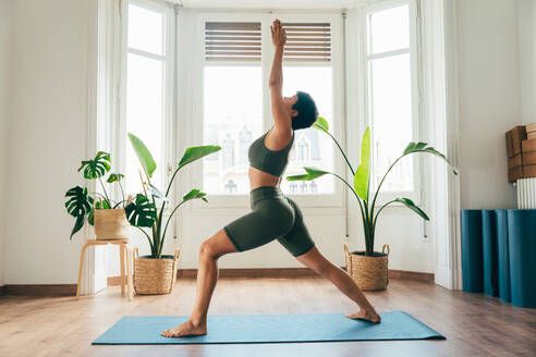 Beautiful sporty girl making yoga training in the gym studio. Young woman coach with short hair performing yoga and acroyoga poses, warming up for the class. Concepts of healthy lifestyle and sport disciplines - DMDF10887