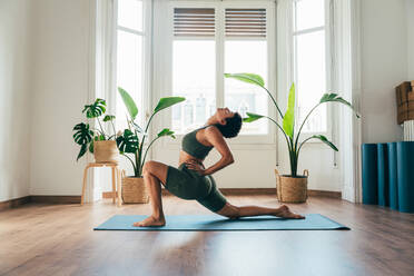 Beautiful sporty girl making yoga training in the gym studio. Young woman coach with short hair performing yoga and acroyoga poses, warming up for the class. Concepts of healthy lifestyle and sport disciplines - DMDF10888