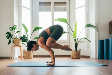 Beautiful sporty girl making yoga training in the gym studio. Young woman coach with short hair performing yoga and acroyoga poses, warming up for the class. Concepts of healthy lifestyle and sport disciplines - DMDF10894