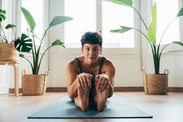 Beautiful sporty girl making yoga training in the gym studio. Young woman coach with short hair performing yoga and acroyoga poses, warming up for the class. Concepts of healthy lifestyle and sport disciplines - DMDF10907