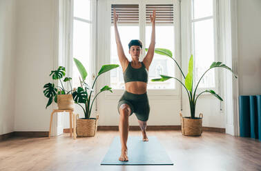 Beautiful sporty girl making yoga training in the gym studio. Young woman coach with short hair performing yoga and acroyoga poses, warming up for the class. Concepts of healthy lifestyle and sport disciplines - DMDF10910