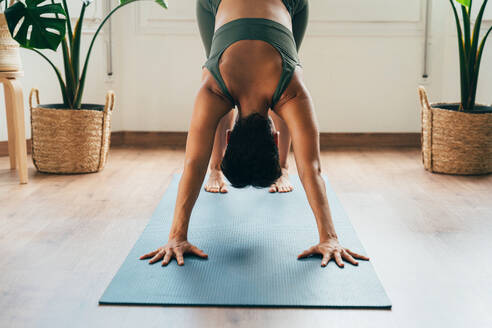 Beautiful sporty girl making yoga training in the gym studio. Young woman coach with short hair performing yoga and acroyoga poses, warming up for the class. Concepts of healthy lifestyle and sport disciplines - DMDF10913