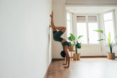 Beautiful sporty girl making yoga training in the gym studio. Young woman coach with short hair performing yoga and acroyoga poses, warming up for the class. Concepts of healthy lifestyle and sport disciplines - DMDF10921