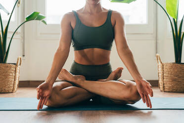 Beautiful sporty girl making yoga training in the gym studio. Young woman coach with short hair performing yoga and acroyoga poses, warming up for the class. Concepts of healthy lifestyle and sport disciplines - DMDF10923