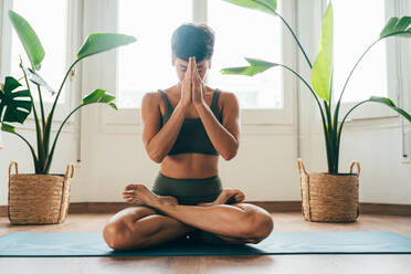 Beautiful sporty girl making yoga training in the gym studio. Young woman coach with short hair performing yoga and acroyoga poses, warming up for the class. Concepts of healthy lifestyle and sport disciplines - DMDF10928