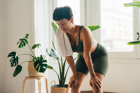 Beautiful sporty girl making yoga training in the gym studio. Young woman coach with short hair performing yoga and acroyoga poses, warming up for the class. Concepts of healthy lifestyle and sport disciplines - DMDF10936