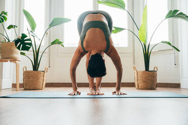 Beautiful sporty girl making yoga training in the gym studio. Young woman coach with short hair performing yoga and acroyoga poses, warming up for the class. Concepts of healthy lifestyle and sport disciplines - DMDF10939