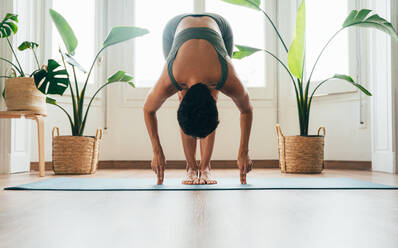 Beautiful sporty girl making yoga training in the gym studio. Young woman coach with short hair performing yoga and acroyoga poses, warming up for the class. Concepts of healthy lifestyle and sport disciplines - DMDF10940