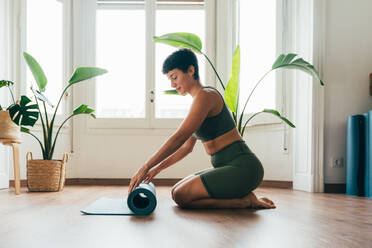 Beautiful sporty girl making yoga training in the gym studio. Young woman coach with short hair performing yoga and acroyoga poses, warming up for the class. Concepts of healthy lifestyle and sport disciplines - DMDF10943