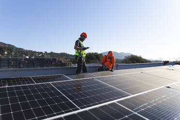 Techniker bei der Installation von Solarzellen auf dem Dach - PCLF00979