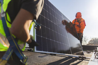 Ingenieure tragen Solarmodul auf dem Dach an einem sonnigen Tag - PCLF00994