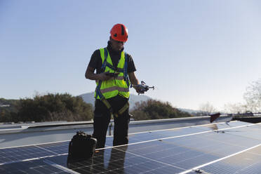 Älterer Techniker mit Drohne vor einem Solarpanel - PCLF00998