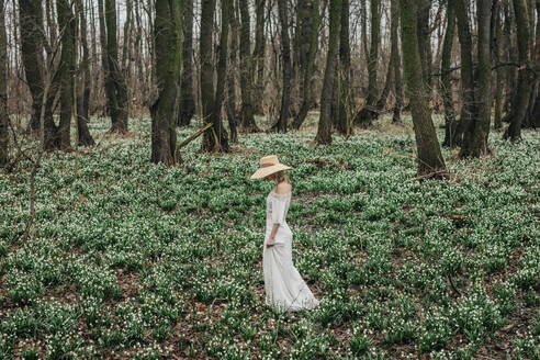 Frau geht inmitten von Blumen im Wald spazieren - VSNF01734