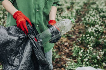 Frau sammelt Plastikflasche im Wald - VSNF01746