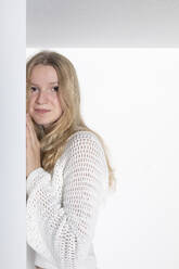 Blond teenage girl standing against white background - PSTF01103