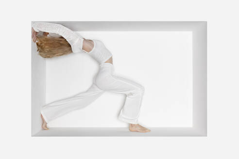 Teenage girl doing handstand against white background - PSTF01109