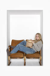 Teenage girl having popcorn sitting on chairs in alcove - PSTF01127