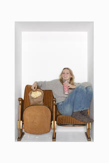 Teenager mit Popcorn und Saft auf Stühlen in einer Nische sitzend - PSTF01129
