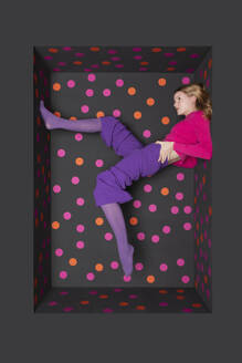 Teenager with legs up over colored dots background - PSTF01261