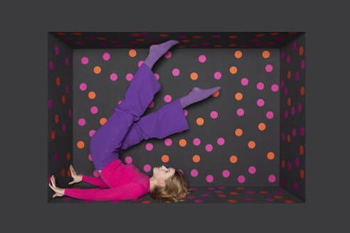 Teenager with legs up over black background with colored dots - PSTF01266
