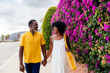 Beautiful mature black couple of lovers dating at the seaside - Married african middle-aged couple bonding and having fun outdoors, concepts about relationship, lifestyle and quality of life - DMDF10980