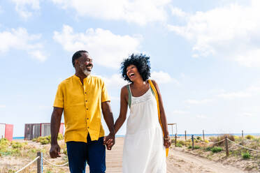 Beautiful mature black couple of lovers dating at the seaside - Married african middle-aged couple bonding and having fun outdoors, concepts about relationship, lifestyle and quality of life - DMDF11020