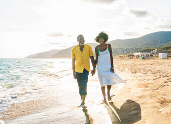 Beautiful mature black couple of lovers dating at the seaside - Married african middle-aged couple bonding and having fun outdoors, concepts about relationship, lifestyle and quality of life - DMDF11090