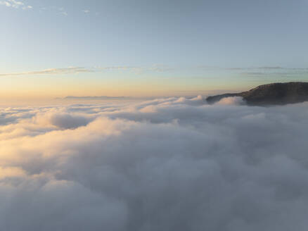 Aerial view of mountain range surrounded by low clouds at sunset and the Amalfi Coast in background as seen from the plane, Salerno, Campania, Italy. - AAEF27703