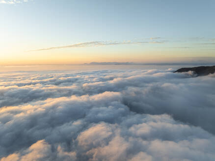 Aerial view of mountain range surrounded by low clouds at sunset and the Amalfi Coast in background as seen from the plane, Salerno, Campania, Italy. - AAEF27709