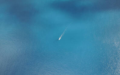 Aerial drone top-down view of a boat in clear blue water at the Eastern Peninsula coastline of Madeira island, Portugal. - AAEF27729