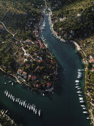 Aerial view of picturesque coastal town with moored boats in transparent turquoise water, Brac Island, Croatia. - AAEF27860